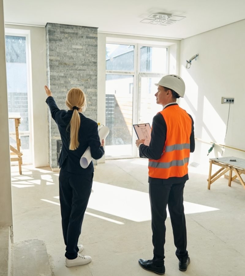 Businesswoman,And,Foreman,Standing,In,Room,Which,Needs,Redecoration